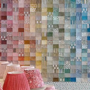 A wall of swatches organized by color like a rainbow. Lampshades in the foreground.