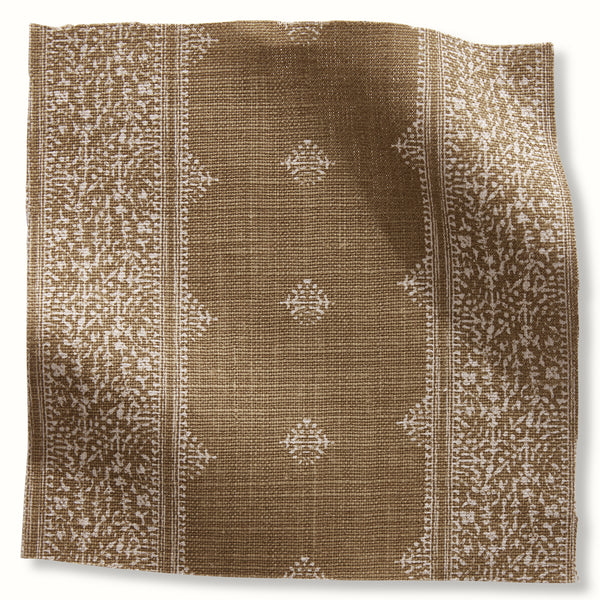 Bronze pillow cover with vertical stripe panels and repeating white geometric motifs