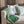 Upholstered sofa with beige upholstery, green throw blanket, patterned accent pillows