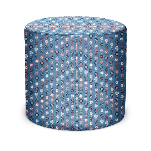 Indoor pouf with round drum shape and blue fabric covered in pink/white floral pattern
