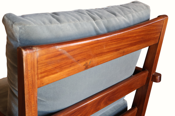 Wooden armchair close-up: carved reddish-brown frame and light blue cushion