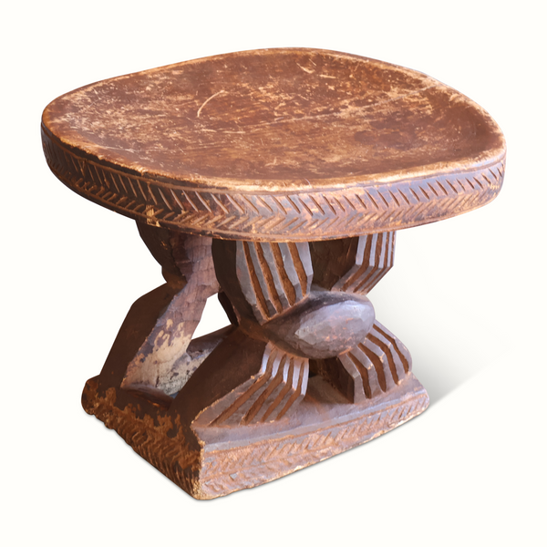 Antique African wooden stool with round carved top and pedestal base, dark brown.