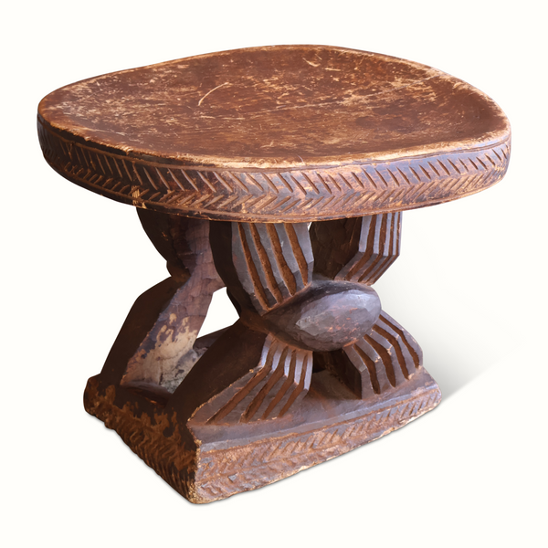 Antique African wooden stool with round seat, carved border, and pedestal legs, dark brown.