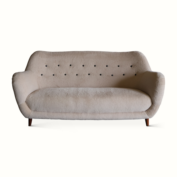 Light gray upholstered sofa with button-tufted back and dark wooden legs.