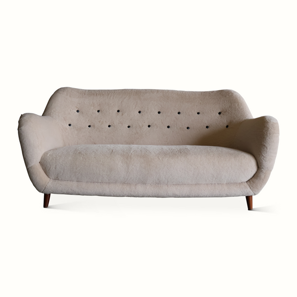 Light gray upholstered sofa, button-tufted back, cushioned seat, dark wooden legs.