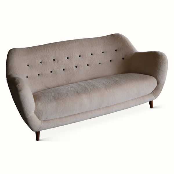 Light gray sofa with button-tufted back panel, rolled arms, and dark wooden legs.