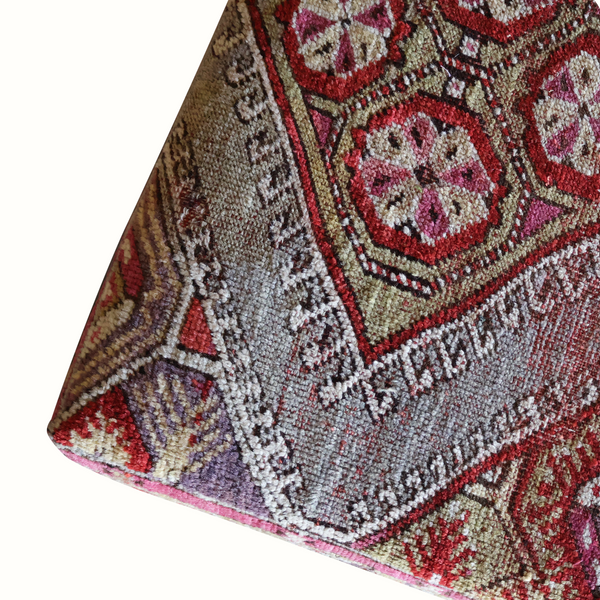Lexington ottoman corner close-up of textured rug weave in gray, red, purple