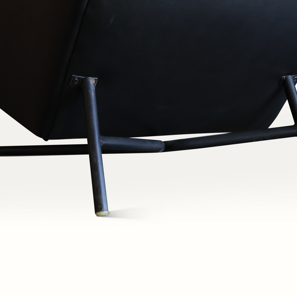Dark leather lounge chair base with metal legs and black upholstery, close-up underside
