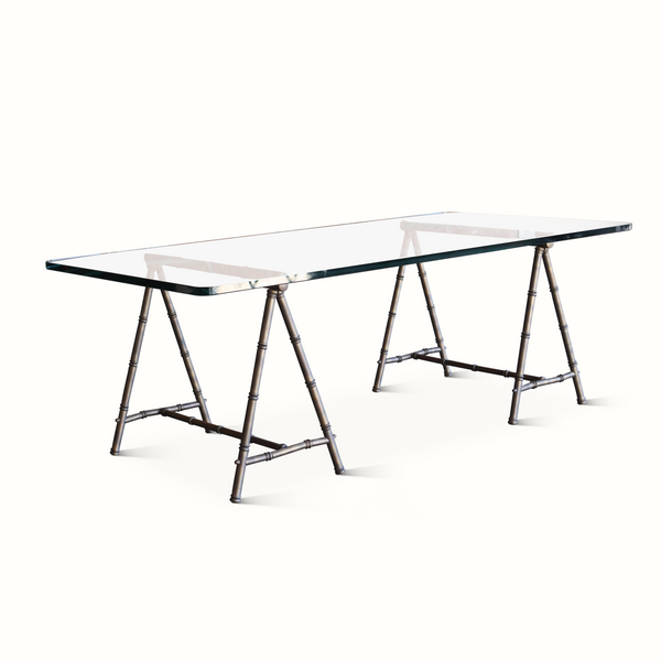Long coffee table with clear glass top and bamboo-style trestle base in dark metal