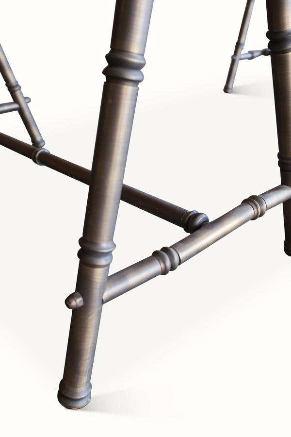 Close-up of bamboo-style trestle leg joints on dark metal coffee table base