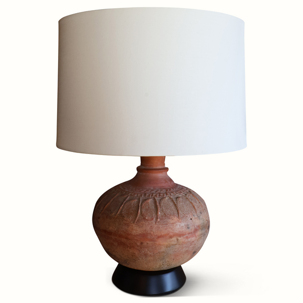 Pottery table lamp with round brown base and carved relief pattern, tan fabric shade