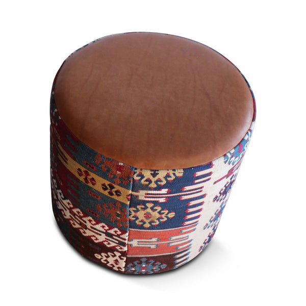 Leather-look top on geometric kilim pouf in red, navy, and cream tones
