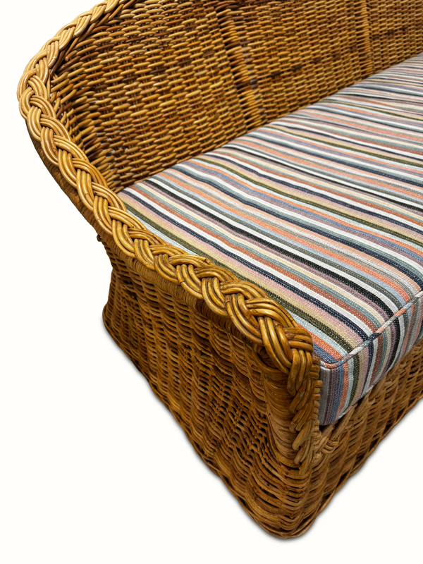 Wicker sofa arm detail with striped cushion cover and braided woven edge