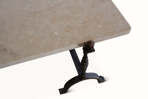Limestone tabletop corner with dark wrought iron leg and arched foot support