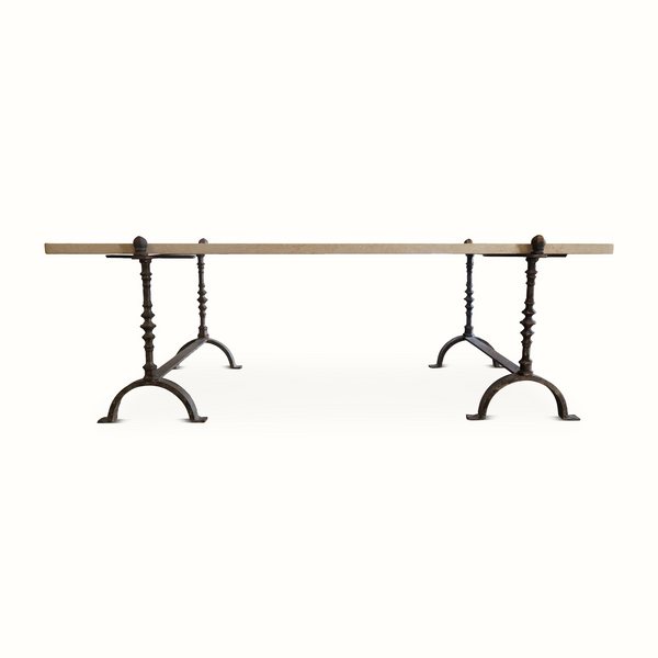 Limestone-topped wrought iron table with turned legs, arched feet, rectangular top