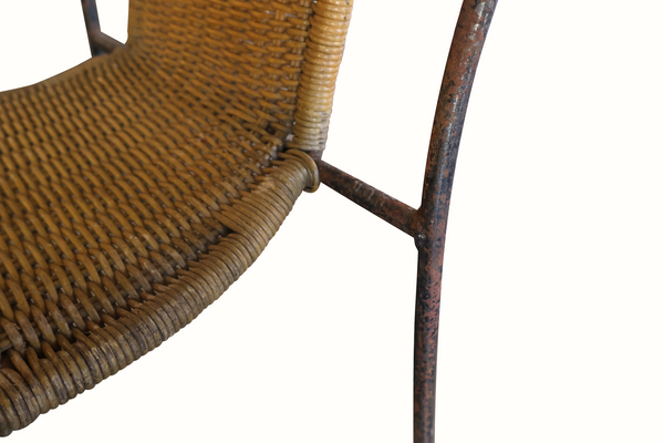 Wicker chair seat close-up with dark iron legs and woven support rails