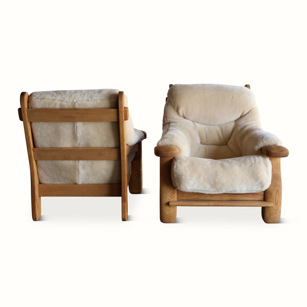 Pair of oak armchairs with light sheepskin upholstery, angled view