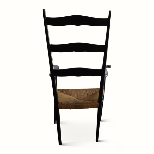 Rush armchair with black frame, wavy back panel, and woven brown seat with tufted center