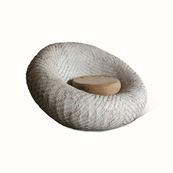 Woven rattan lounge chair with curved oval shape and beige seat cushion