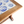 Close-up of blue-and-white Delft tile inset on wooden table corner with turned leg