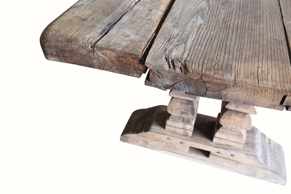 Close view of farm table corner with planked top edge and carved base support