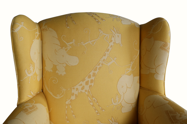 Yellow wingback armchair backrest detail with light animal circus pattern and rolled arms