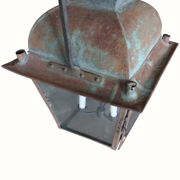 Hanging metal lantern from an angle with rust and teal patina, front chimney and glass sides