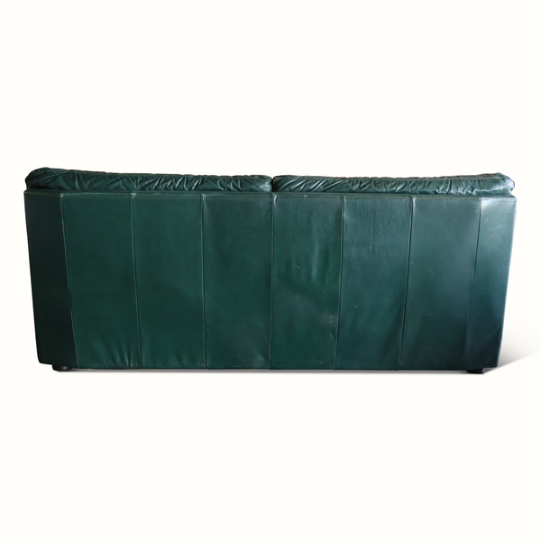 Dark green leather sofa back side with panel seams and short legs