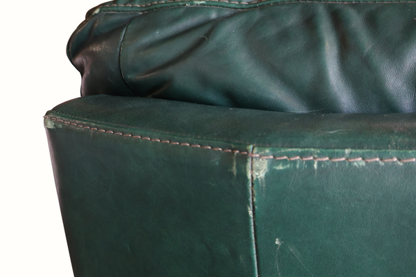 Dark green leather sofa corner detail with visible stitching and creases
