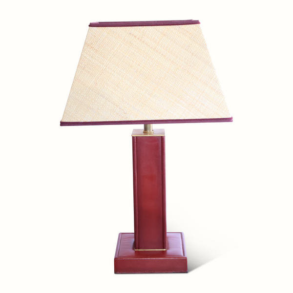 Red leather table lamp with beige fabric shade and dark trim, brass accents.