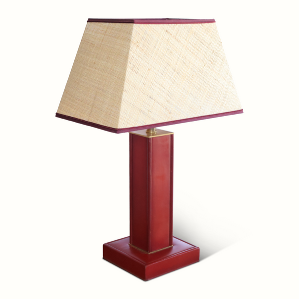 Red leather table lamp with beige fabric shade and dark border, brass finial.
