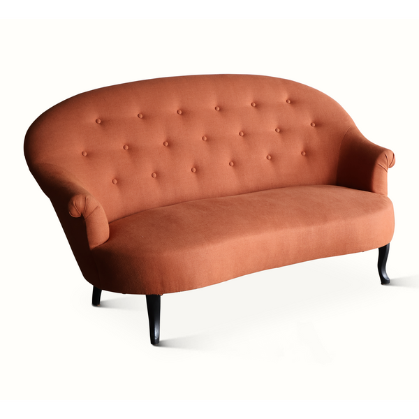Orange-brown velvet sofa with button-tufted back, rolled arms, and dark tapered legs
