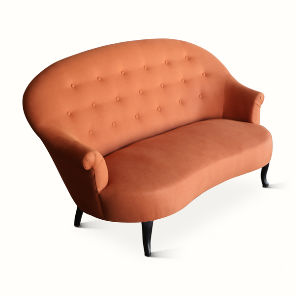 Tufted orange-brown velvet sofa with curved arms and turned dark legs