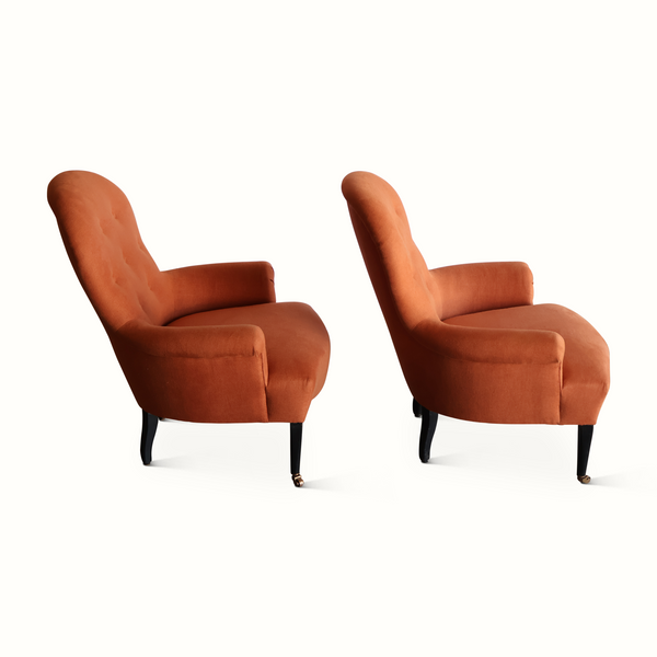 Two Napoleon III armchairs with terracotta upholstery, rounded backs, and curved arms