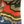 Woven landscape tapestry corner with orange road, blue water, green trees, fringed edge