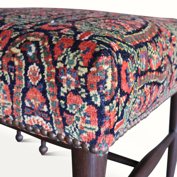 Patterned fabric seat with nailhead trim on dark wooden stool leg