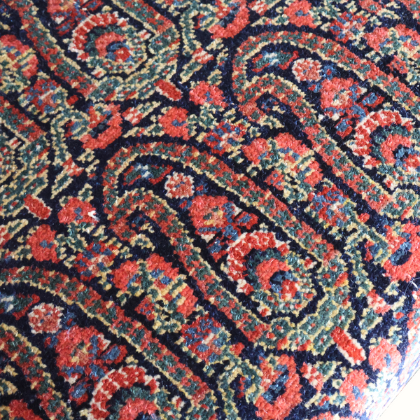 Close-up of vintage Persian carpet-style upholstery fabric in red, blue, and cream