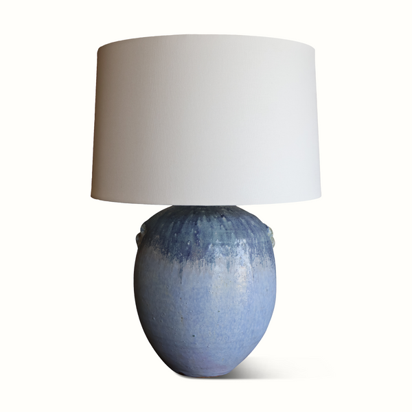 Blue glazed ceramic table lamp with off-white drum shade and rounded bulb base