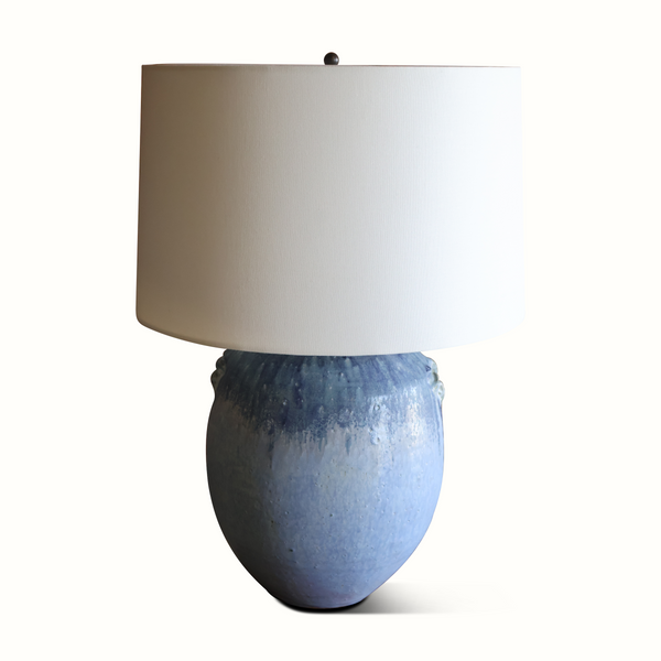 Blue glazed ceramic table lamp with off-white drum shade and small socket cap