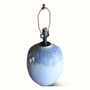 Blue glazed ceramic table lamp with metal harp, socket hardware, and off-white shade