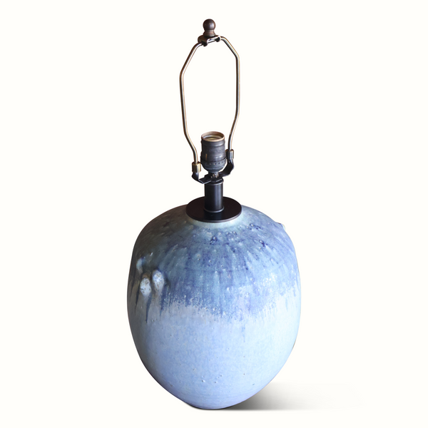 Blue glazed ceramic table lamp with metal harp, socket hardware, and off-white shade