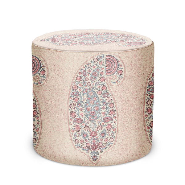 Beige upholstered cylindrical indoor pouf with paisley medallion pattern and pink accents