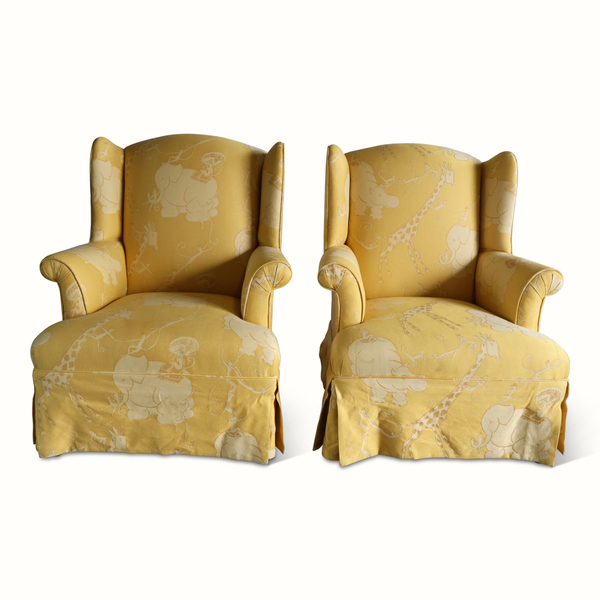 Pair of yellow wingback armchairs with light animal circus pattern upholstery and cushioned seats
