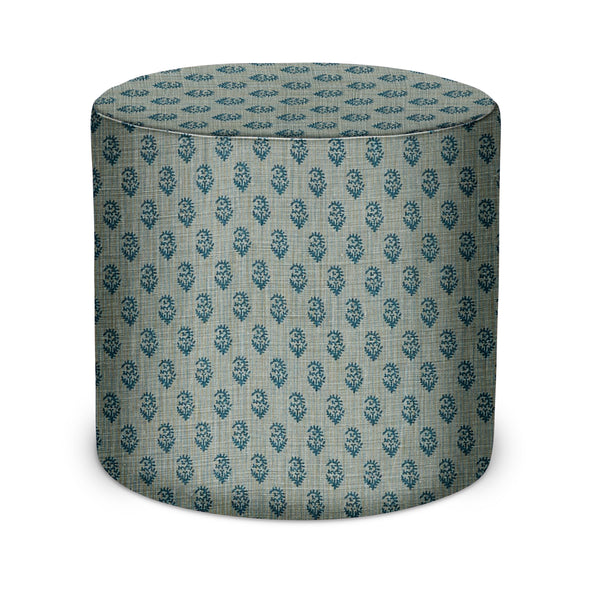 Blue upholstered round indoor pouf with repeating teal and navy pattern