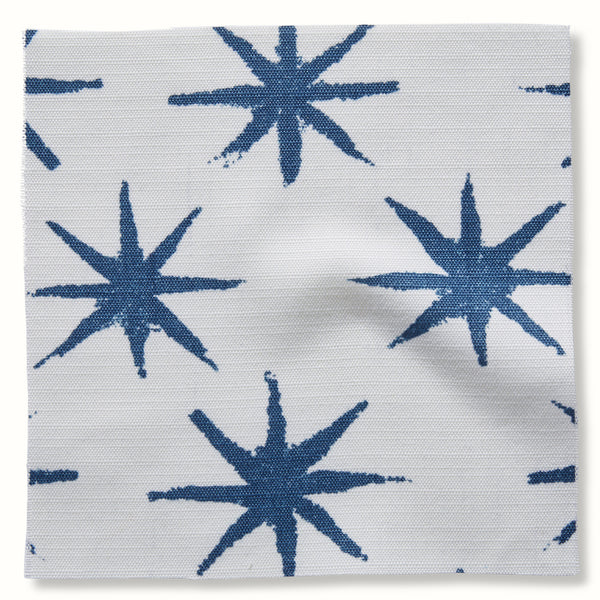 Outdoor pillow cover fabric with indigo starburst pattern on light background