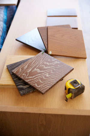 A close up of oak wood samples in a workshop environment, with a measuring tape nearby.