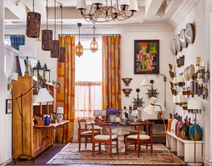 An image of a shop packed with vintage and new lighting, furnishings, and orange curtains.