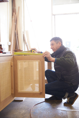 Founder Peter Dunham inspecting a prototype fo a credenza at a woodworking workshop.