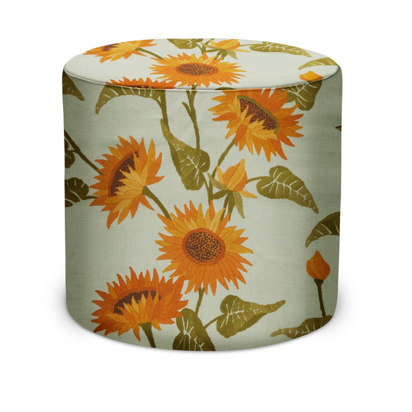 Round indoor pouf ottoman with sunflower vine fabric, light green base and orange floral pattern.