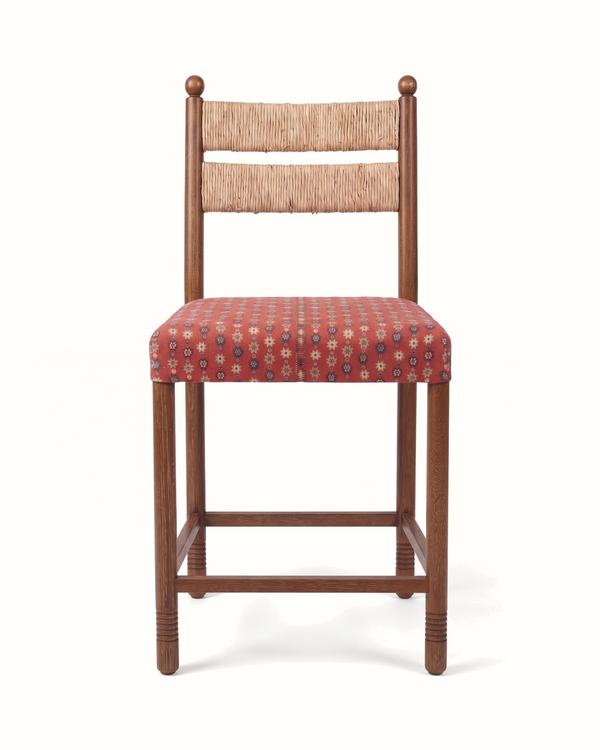 Upholstered counter stool with woven rush back and red patterned seat cushion